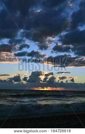 Sunset over the sea behind the clouds