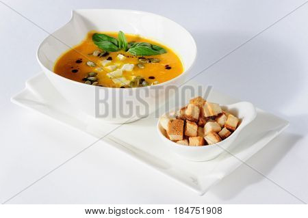 Roasted pumpkin soup with croutons on white background. Copy space.