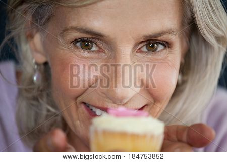 Close up portrait of woman holding cupcake at cafe shop