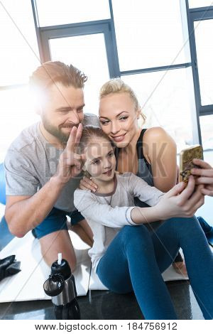 Girl Taking Self Portrait With Parents At Fitness Center