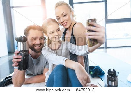 Girl Taking Self Portrait With Parents At Fitness Center