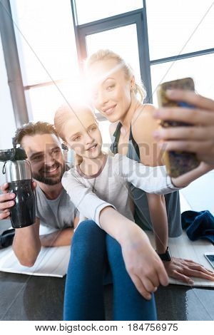 Girl Taking Self Portrait With Parents At Fitness Center