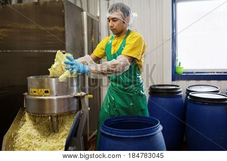 ST. PETERSBURG, RUSSIA - FEBRUARY 28, 2017: Worker of the food processing company Factory of Homemade Pickles shredding the cabbage using the industrial shredder
