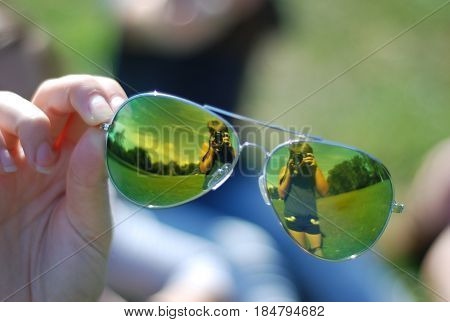 girl taking photo mirrored in sunglasses ..