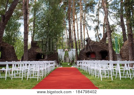 Beautiful Wedding Ceremony Outdoors. Decorated Chairs Stand On The Grass. Wedding Arch Made  Flowers