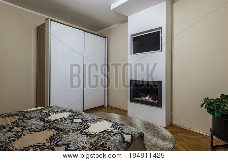 Fireplace And Warderobe With Double Bed In Bedroom Interior