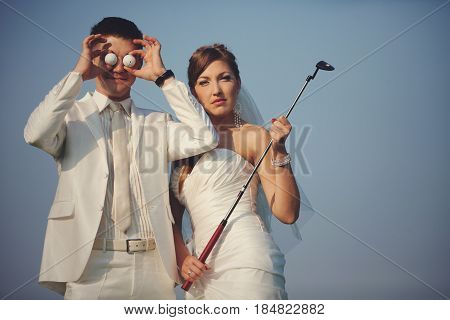 Groom Holds Golf Balls In The Front Of His Eyes While Bride Holds A Mashy