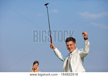 Groom Raises His Hands Like A Winner Holding A Golf Mashy
