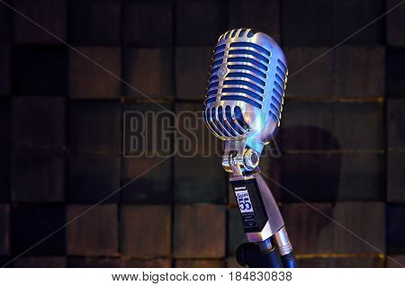 MINSK BELARUS - SEPTEMBER 29 2015: Silver old fashioned stage microphone- SHURE Super 55 Deluxe against wood background. Room for sound recording concept.