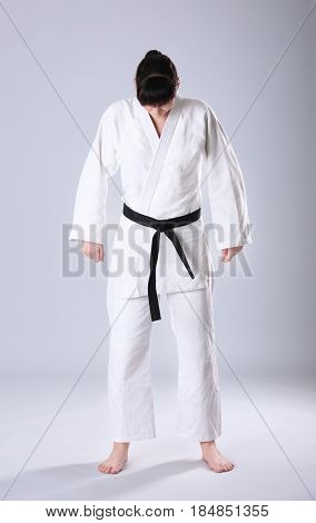 Young sporty woman in kimono on light background