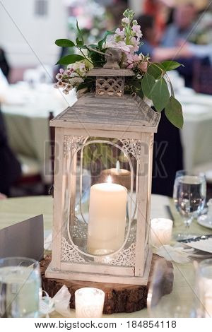 Wedding reception centerpiece with a location seating sign, candles, and flowers ont he table.