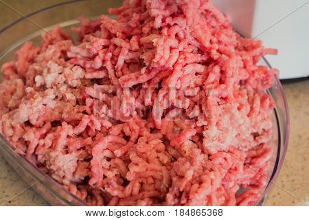 Closeup of minced raw meat coming out from grinder