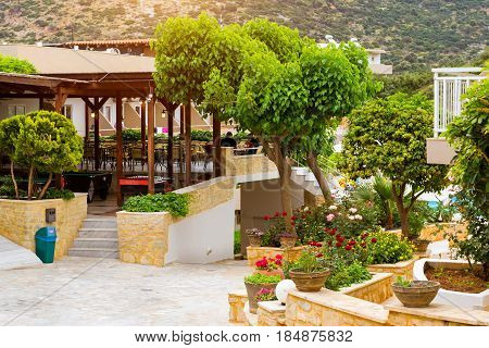 Modern and classic resort Greek architecture. Landscaping and gardening local area. White building of houses stands on shore of Cretan sea. Resort village Bali Rethymno