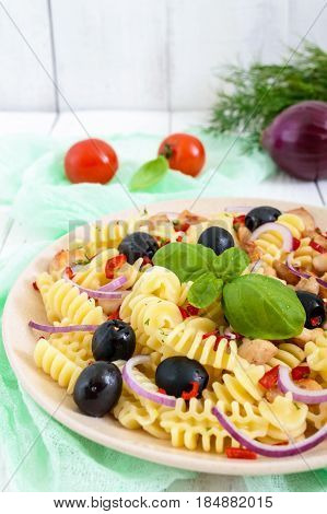Pasta salad radiatori with chicken black olives blue onion sweet pepper on a white wooden background. Vertical view