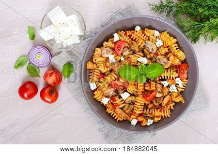 Pasta Radiatori with chicken mushrooms cherry tomatoes feta cheese and tomato sauce on a light background. Top view.