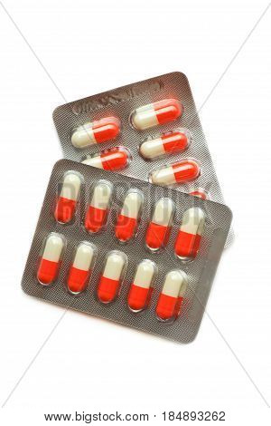 two packs of white and orange multicolored pills capsules in blister isolated on white. Flat lay; top view.