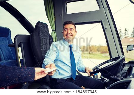 transport, tourism, road trip and people concept - smiling bus driver taking ticket or plastic card from passenger