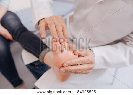 Testing reflexes. Delicate dedicated wonderful expert trying not hurting his patient while conducting a checkup on the joints functioning