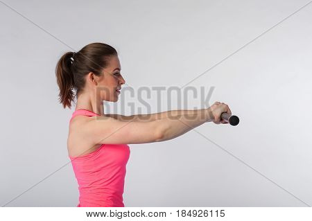 Young fit woman exercising with bodybar. Sporty girl wearing pink top posing on white background. Fitness concept.