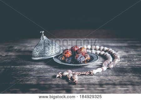 Date-palm is placed on silver. date palm fruits or kurma ramadan on a wooden black background.