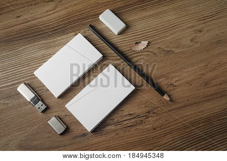 Photo of blank stationery set. Bank business cards pencil eraser and flash drive on wood table background. Responsive design mockup. Top view.