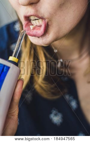 A Woman Using An Oral Irrigator In Bathroom