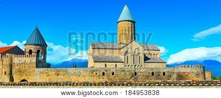 Panoramic banner view of Alaverdi orthodox monastery in Kakhetia region in Georgia and snow peaks of Caucasus mountains
