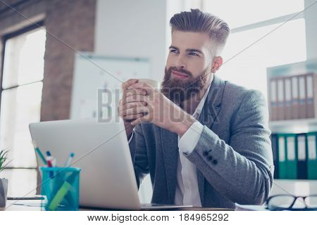 Young Dreaming Worker Is Thinking In Front Of Laptop At Work Place. He Is Happy, Smiling