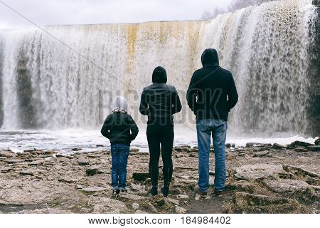 Young family watches Jagala Waterfall, the highest natural waterfall in Estonia with height about 8 meters.
