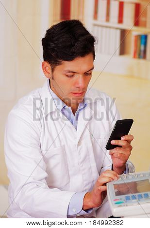 closeup shot young male technician testing digital photocopier machine while he is using his celphone.