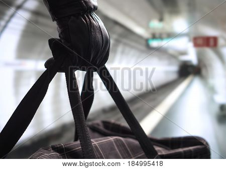 Close up of terrorist holding black bag in hand, possibly timebomb. Man planning a dangerous explosion in subway. Underground metro tunnel in the blurred background. Terrorism and security concept.
