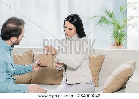 Psychotherapist With Clipboard Giving Paper Tissues To Upset Young Patient With Glass Of Water