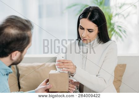 Bearded Psychotherapist Giving Paper Tissues To Upset Young Patient In Office