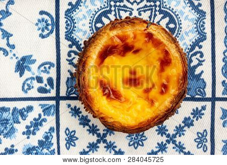 A Single Pastel de Nata On Traditional Blue And White Azulejo Tile Towel Background