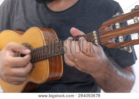 Young Man Playing Ukulele With Shirt And Black Pants.