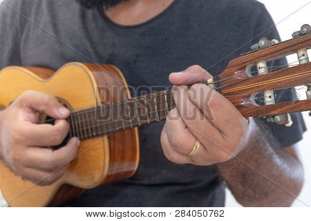 Young Man Playing Ukulele With Shirt And Black Pants.