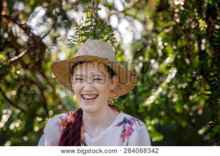 Laughing Pretty Girl In Straw Hat Standing With A Fine Gossamer Spider Cobweb Amongst The Trees