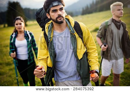 Gorup Of Friends Climbing Up Hill, With Backpacks And Climbing Stick