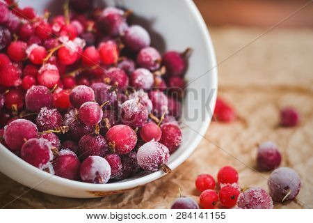 Red Frozen Berries Of Currant And Gooseberry, Covered With White Frost, In A White Plate And On The 