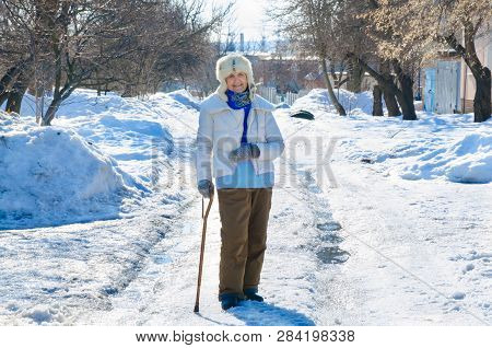 Grandmother With Cane On Road In Park . Old Person Leaning On A Walking Stick. Caucasian Female Seni