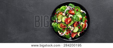 Spinach Salad With Fresh Cucumbers, Tomato, Onion, Pomegranate, Sesame Seeds And Cashew Nuts On Blac