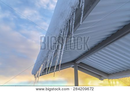 Frosted Roof With Icicles Against Cloudy Sky