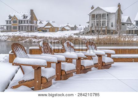 Snowy Chairs On A Lake Deck Against Homes In Utah