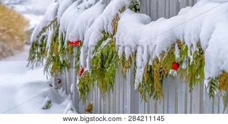 Wooden Fence With Festive Garland Covered In Snow