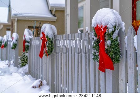Wreaths With Ribbons On A Snowy Fence In Winter