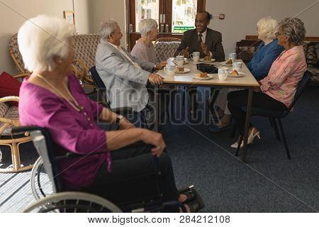 Disable senior woman with happy group of senior friends having fun at nursing home