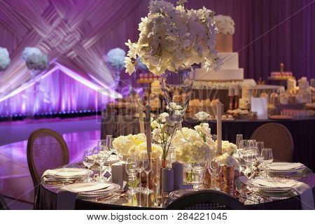 Moody backlit ambience of a wedding reception, luxury elegant table setting