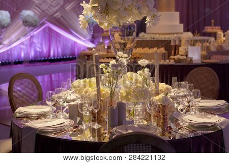 Moody backlit ambience of a wedding reception, luxury elegant table setting