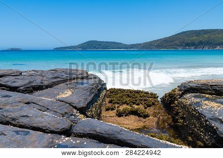View Over Rocks At Pebbly Beach, A Popular Camping Area With Great Surfing Beach And Bush Walks With