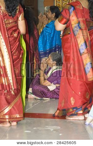 An Older Female Hindu Devotee Sits On The Floor And Prays During The Chariot Festival At The Richmon